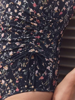 Zwart met broderie en fijne print - Badpak met vormgevende zijrimpeling en buikcorrectie*Next Clearance