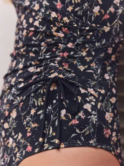 Zwart met broderie en fijne print - Badpak met vormgevende zijrimpeling en buikcorrectie*Next Clearance